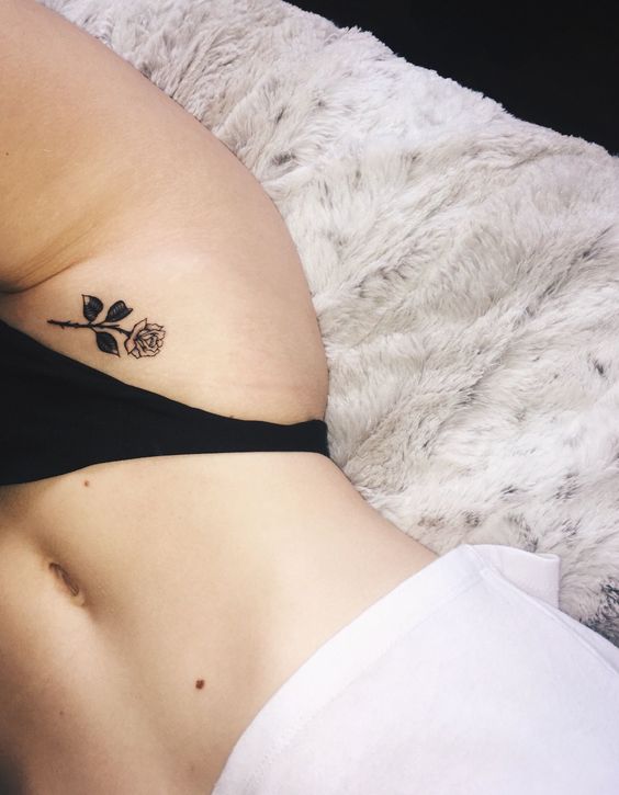 Feminine black rose tattoo on the hip