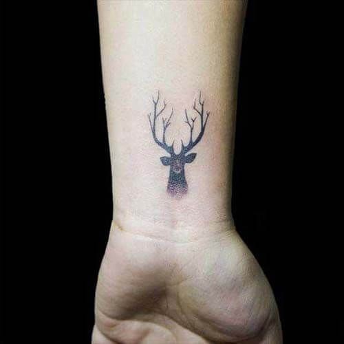 A small head of a deer tattoo on the wrist
