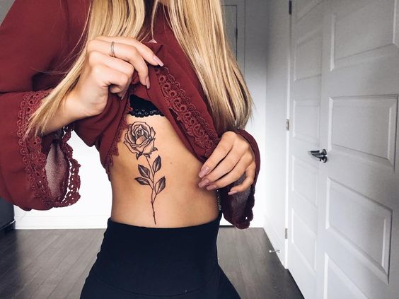 Black rose tattoo on the rib