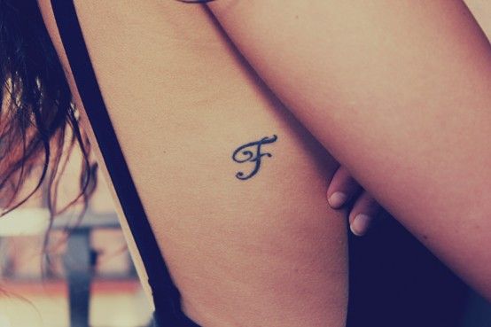 Letter F initial tattoo on a rib cage
