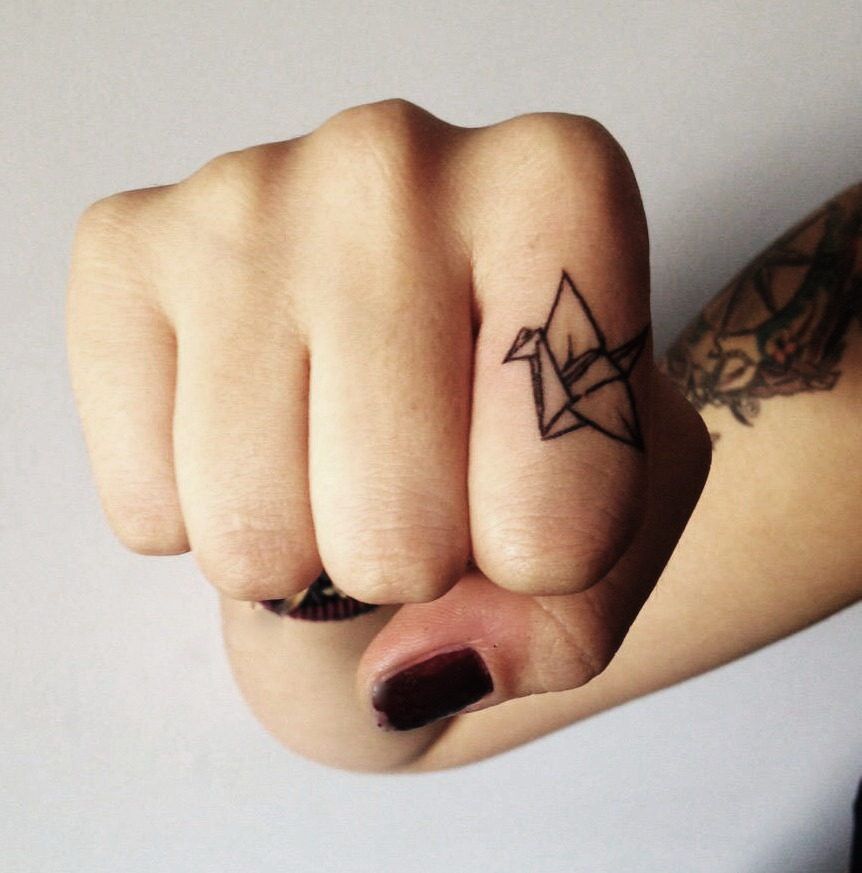 Paper crane tattoo on a finger