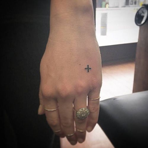 Plus sign tattoo on the left hand by tattooist East