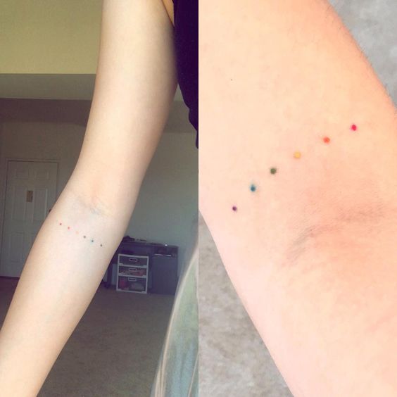Small rainbow dots equality tattoo on the inner arm
