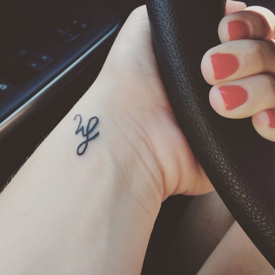 Tiny initial tattoo on a wrist