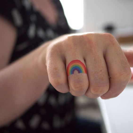 Tiny rainbow gay pride tattoo on the ring finger