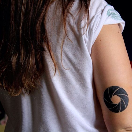 Black aperture tattoo on the back of the arm