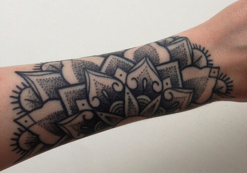 Black dotwork mandala tattoo on the forearm
