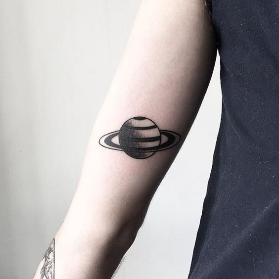 Black handpoked Saturn tattoo on the arm