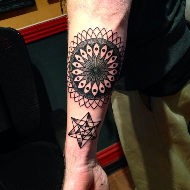 Black mandala tattoo with another geometric shape on the forearm