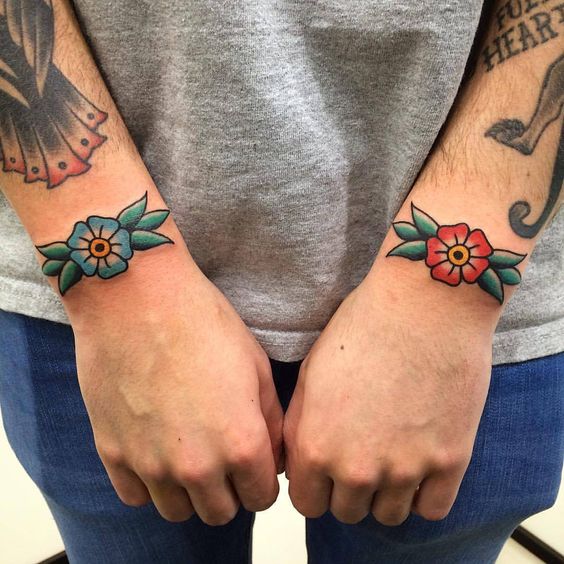 Blue and red traditional flower tattoos on wrists