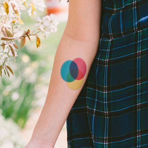 CMYK colored circles tattoo on the arm