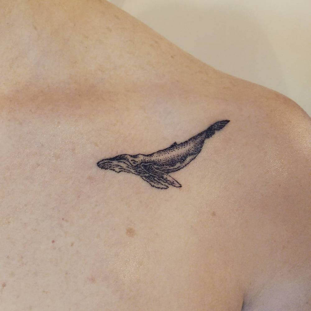 Hand poked whale tattoo on the left clavicle