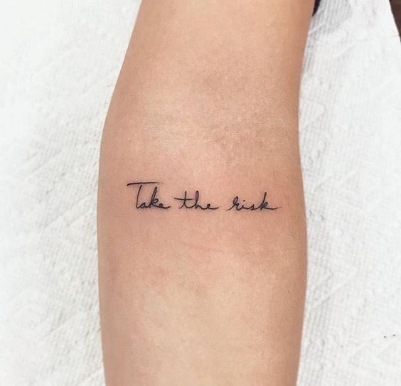 'Take the risk' quote tattoo on the arm.