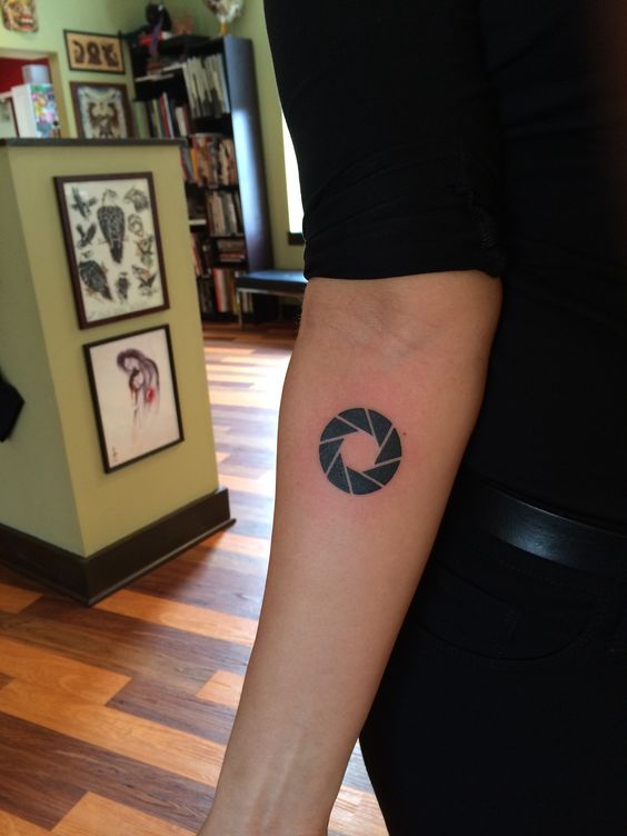 Tattoo of an aperture on the inner arm