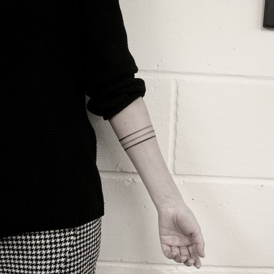 Three black thin lines tattoo on the left arm