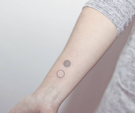 Three little circles tattoo on the right forearm