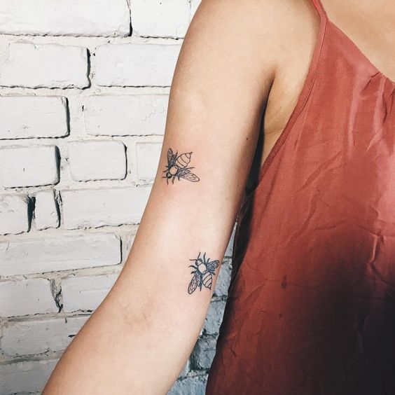 Two tiny bees tattoo on the arm