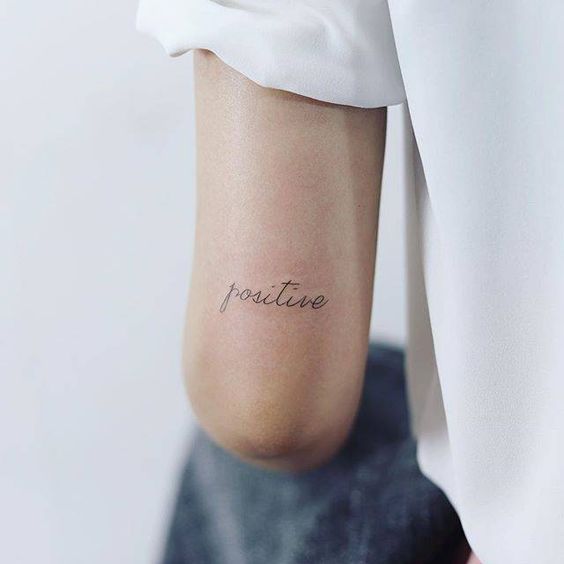 Word positive tattoo on the back of the left arm