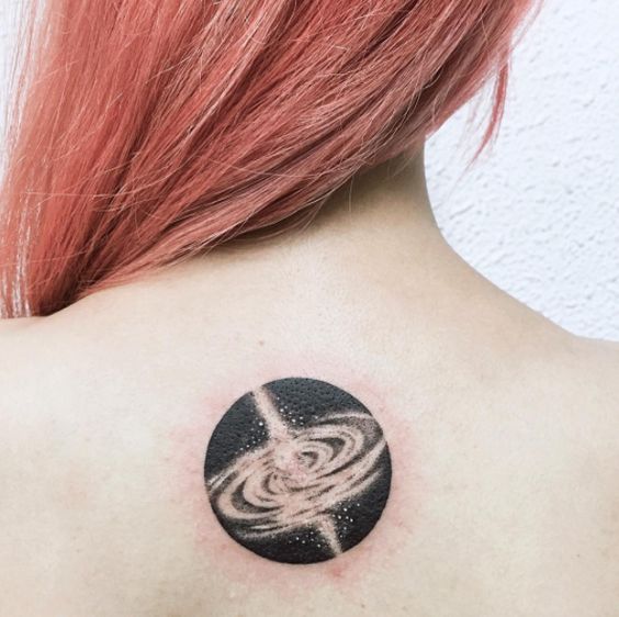 Black circular galaxy tattoo on the upper back