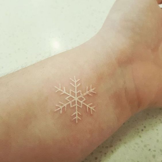 Bold white snowflake tattoo on the wrist