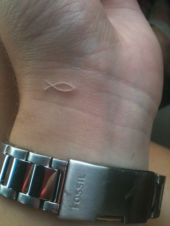 Christian tattoo idea of a micro white fish on the wrist