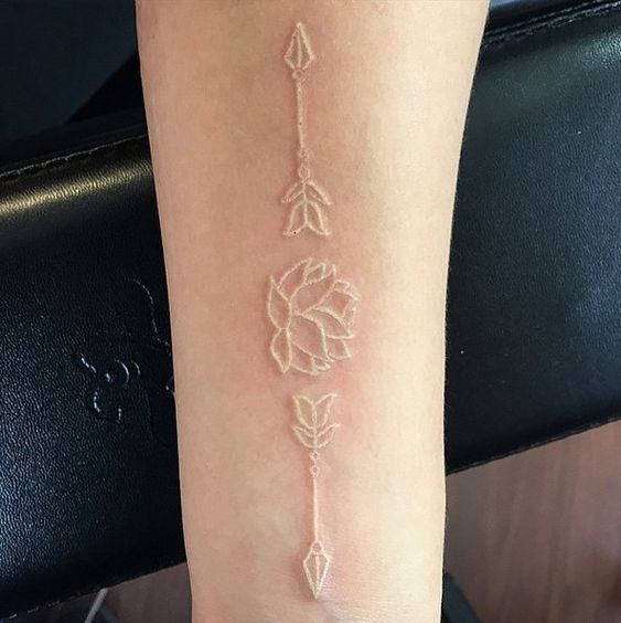 Lotus flower with two arrows tattoo on the arm