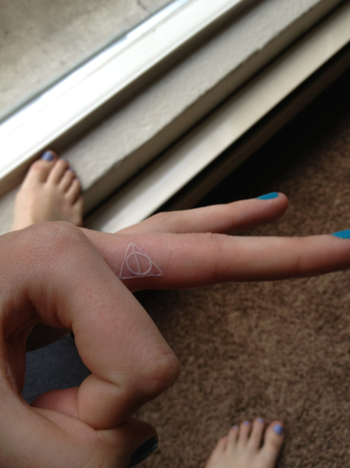 Tiny Harry Potter Deadly Hallows symbol tattoo on the middle finger