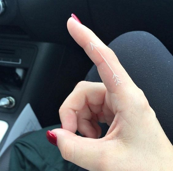 Tiny white arrow tattoo on the pointer finger