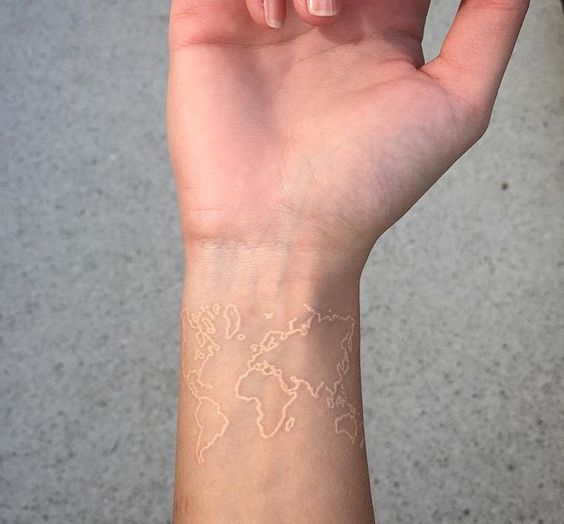 World map white tattoo on the wrist