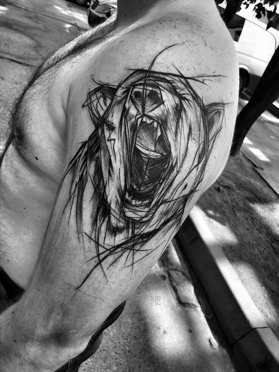 Abstract tattoo of a black paintbrush stroke bear on the left arm