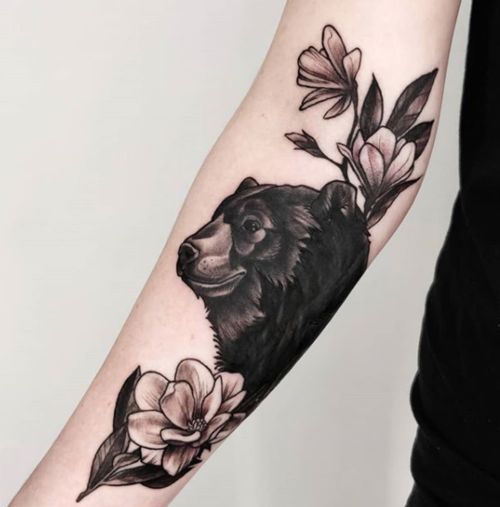 Black bear with flowers tattoo on the outer forearm