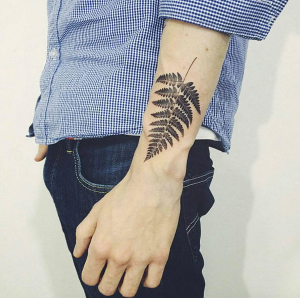 Black fern leaf tattoo on the left wrist by tattooist doy