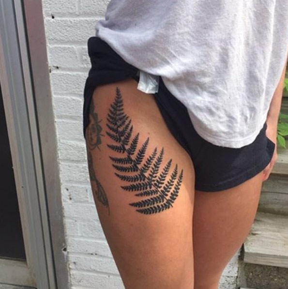 Black fern leaf tattoo on the right thigh