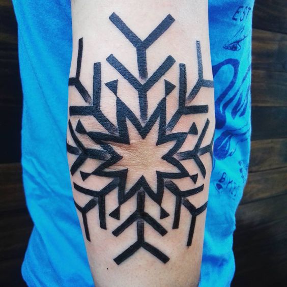 Black outline snowflake tattoo on the right elbow