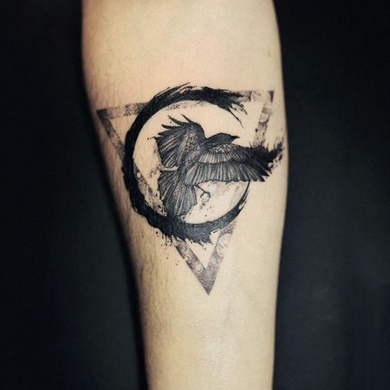 Black paintbrush stroke circle triangle and raven tattoo on the arm