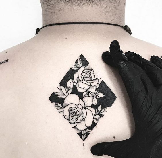 Black rhombus with negative space roses tattoo on the back