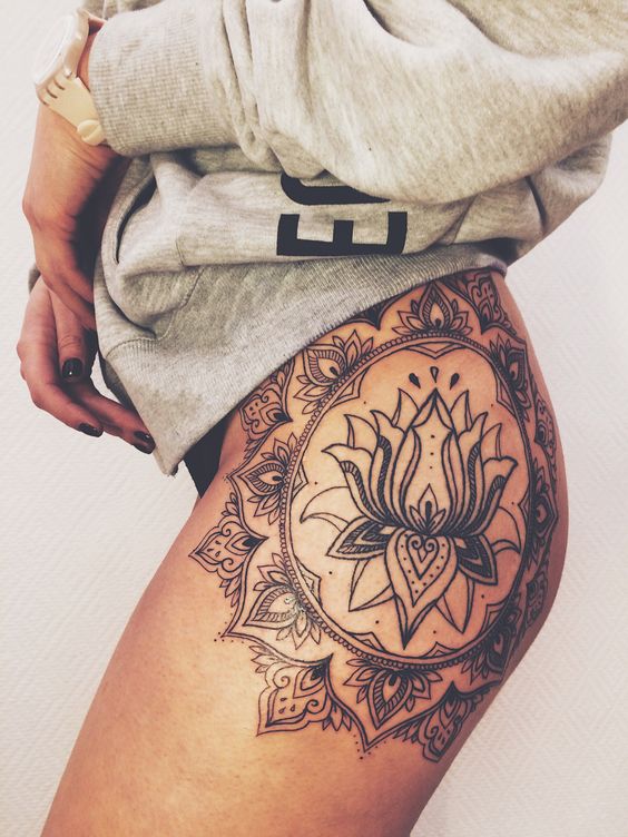 Black tattoo of a lotus flower on the left hip