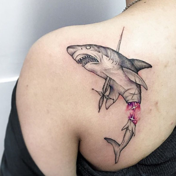 Black tattoo of a vanquished shark on the left shoulder blade