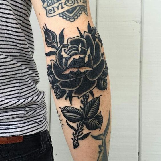 Black traditional rose tattoo on the right elbow