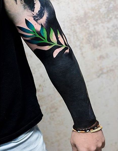 Blackout arm and negative space fern leaf tattoo