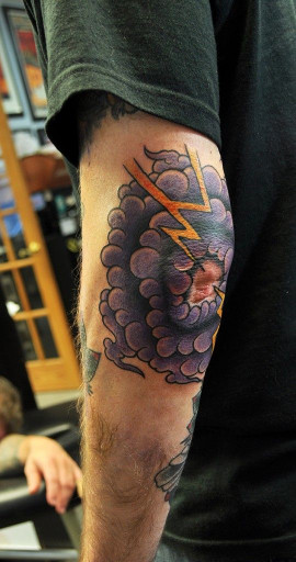 Clouds and thunder tattoo around the left elbow