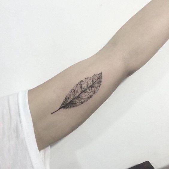 Decayed black leaf tattoo on the left inner arm