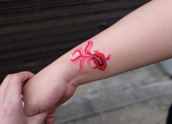 Delicate goldfish tattoo on the wrist