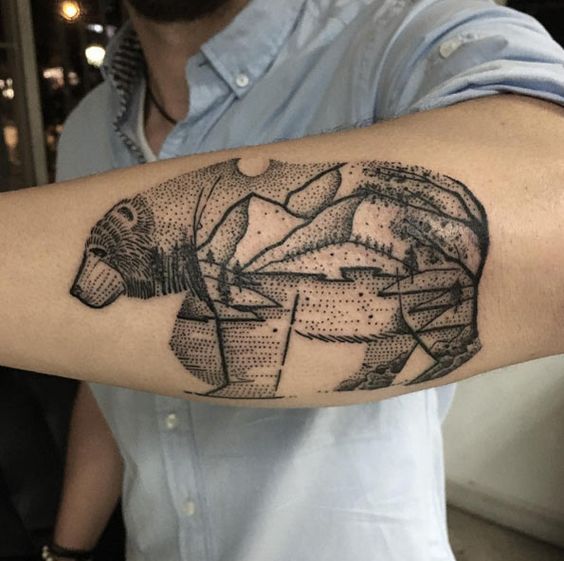 Dotwork style tattoo of a bear with a landscape on the left forearm