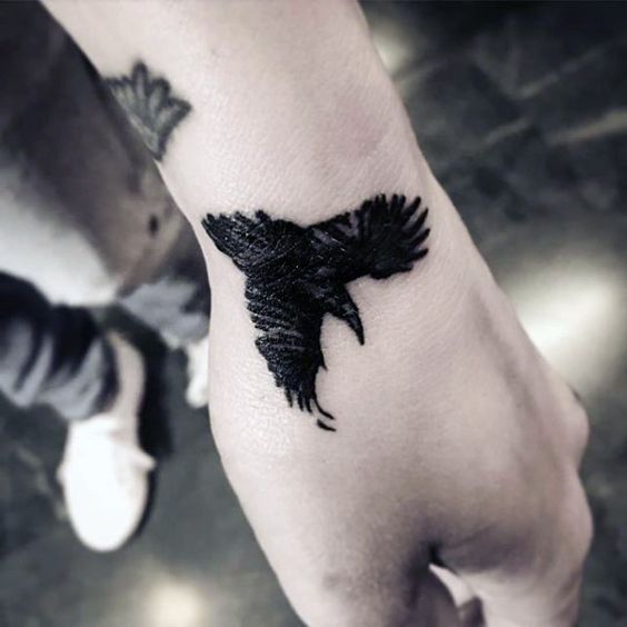 Flying black raven tattoo on the hand