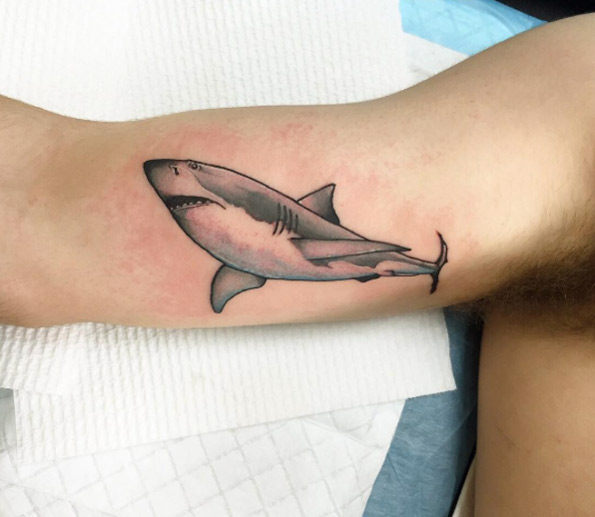 Grey tattoo of a shark on the right bicep