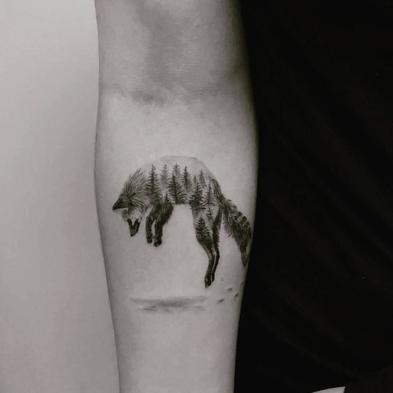 Jumping fox with forest landscape tattoo on the right inner arm