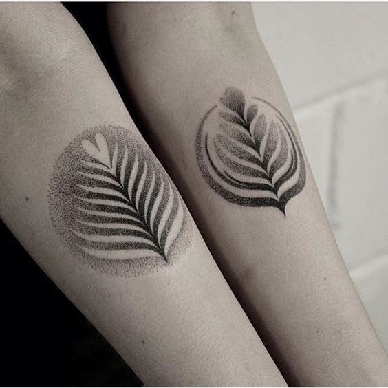 Matching dot work style latte leaf tattoos on arms