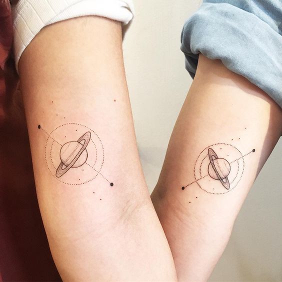 Matching saturn tattoos on arms