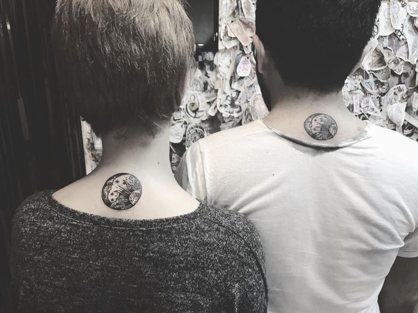 Matching sun and moon circular tattoo on the back of the neck for a couple